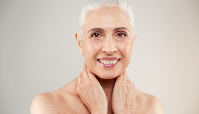 Image of a n amazing naked elderly woman posing isolated over grey background. Looking camera.